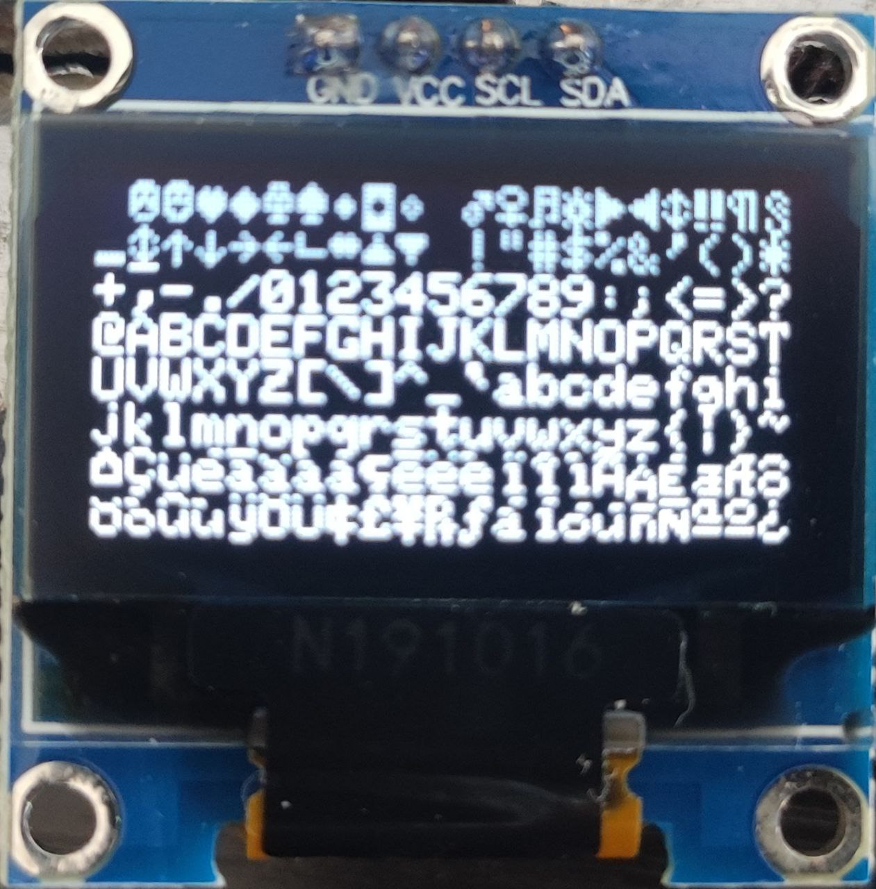 Foto de la pantalla OLED mostrando todos los caracteres del vocabulario inglés incluyendo números, signos de puntuación y letras mayúsculas y minúsculas.